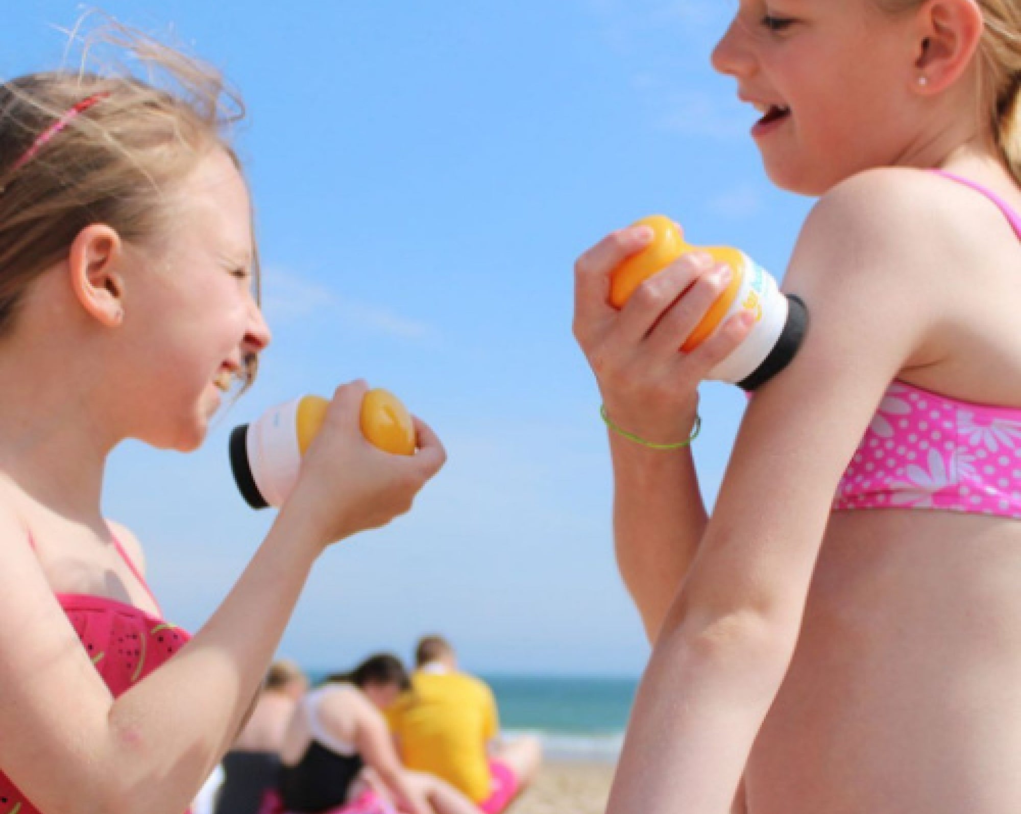 two girls applying sunscreen with solar buddies