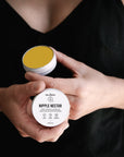 Person holding an open tin of Nipple Nectar balm, a breastfeeding aid to soothe and support skin tissue